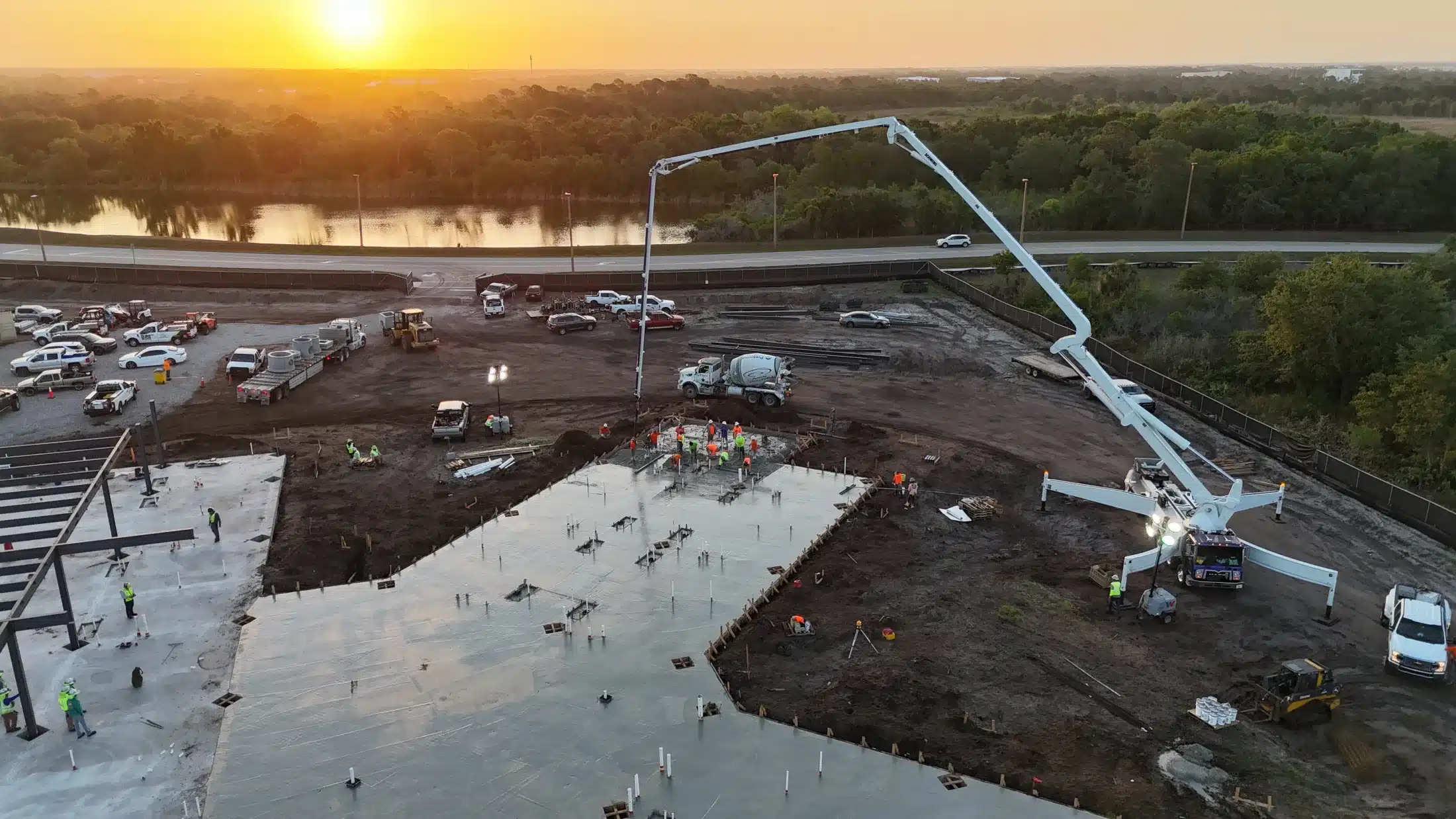 Large commercial slab pour at sunset with concrete pump truck