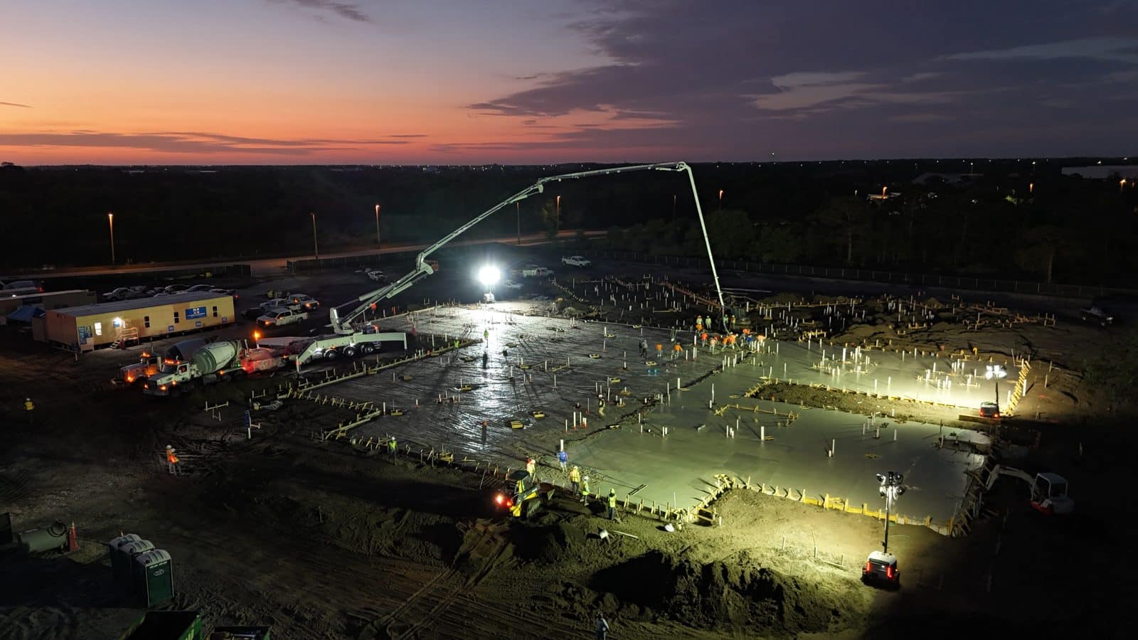 Twilight commercial slab pour with a concrete pump truck and anchor bolts set