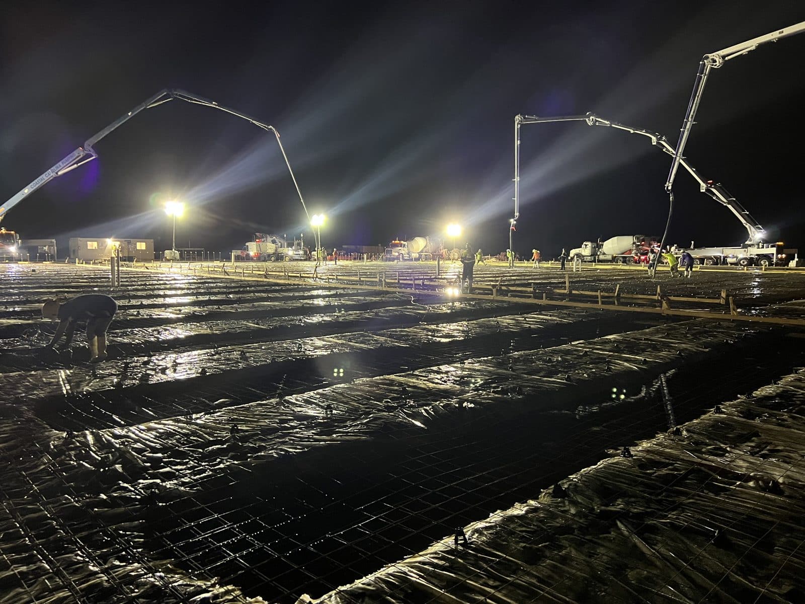 Reinforced slab prep with vapor barrier and pump trucks during a night pour