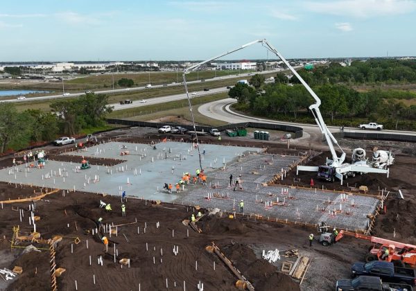 Daytime commercial slab-on-grade pour with anchor bolts set in the deck